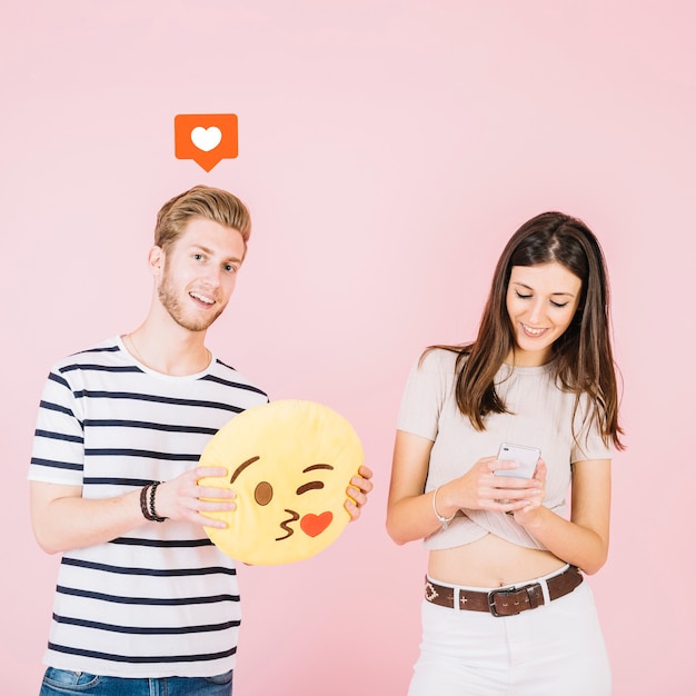 Wie ikone über dem mann, der kuss emoji nahe ihrer freundin unter verwendung des smartphone hält