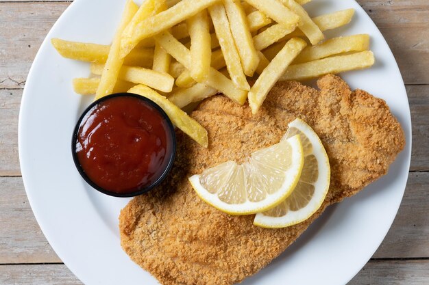 Wiener Schnitzel mit Bratkartoffeln auf Holztisch