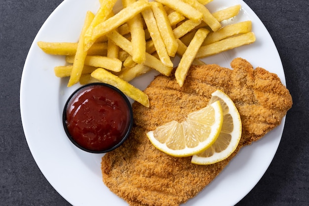 Wiener Schnitzel mit Bratkartoffeln auf schwarzem Hintergrund
