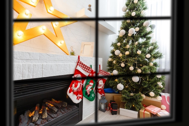 Kostenloses Foto wiew durch das fenster, weihnachtsbaum im hintergrund, winterurlaubskonzept,