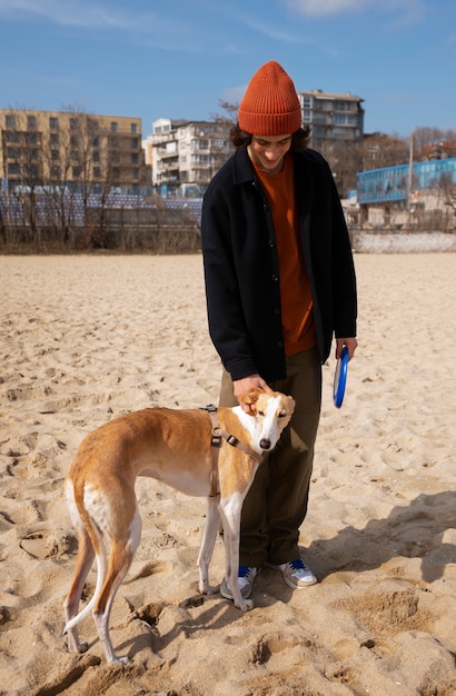 Kostenloses Foto windhund mit männlichem besitzer am strand