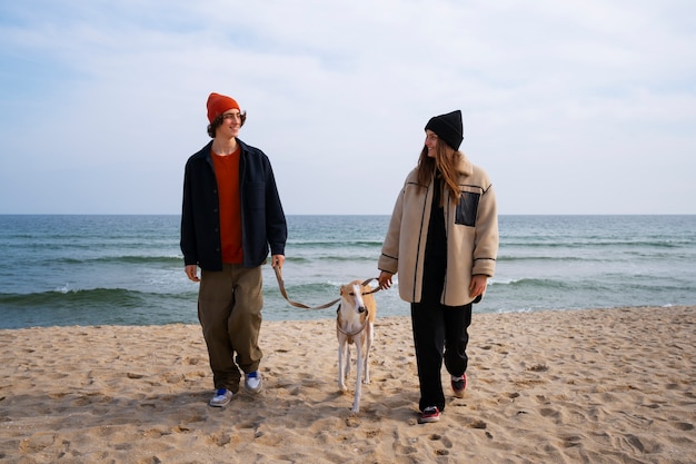 Kostenloses Foto windhund mit paarbesitzern am strand