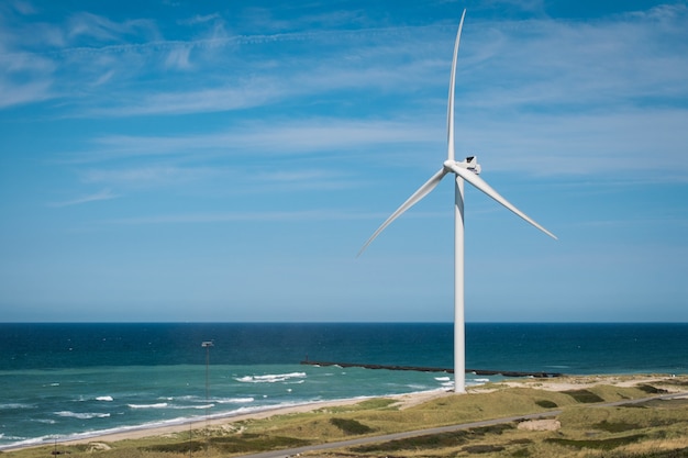 Windmühle am Strand in der Nähe des schönen Meeres unter dem bewölkten Himmel