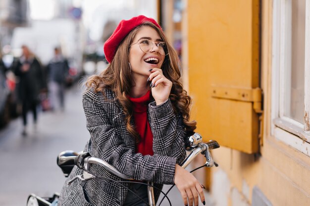 Winsome weißes Mädchen, das ihr Fahrrad durch Stadt fährt