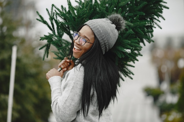 Winterkonzept. Frau in einem grauen Pullover. Verkäuferin von Weihnachtsbaum.