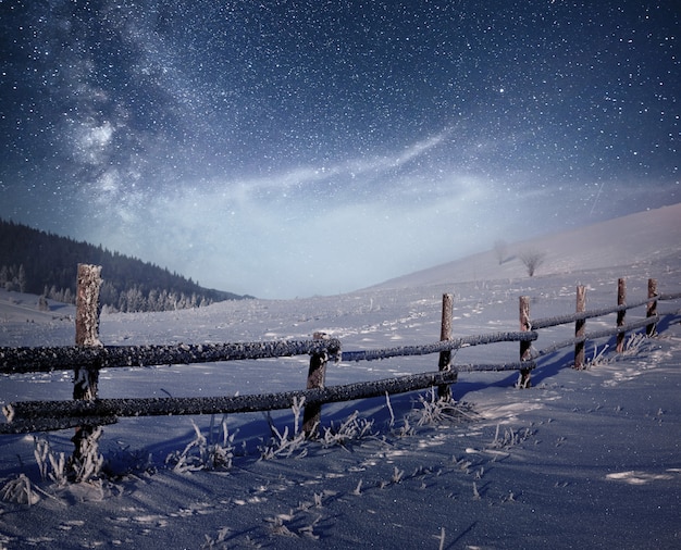 Winterlandschaft. Bergdorf in den ukrainischen Karpaten. Lebendiger Nachthimmel mit Sternen und Nebel und Galaxie. Deep Sky Astrophoto