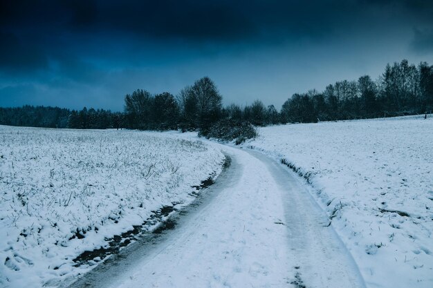 Winterstraße durch verschneite Landschaften und Wälder, Winterabend auf dem Land