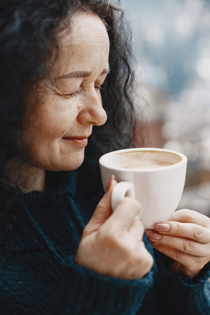 Winterurlaub in den Bergen. Lockiges Haar bei Frauen. Weiße Tasse mit Kaffee.