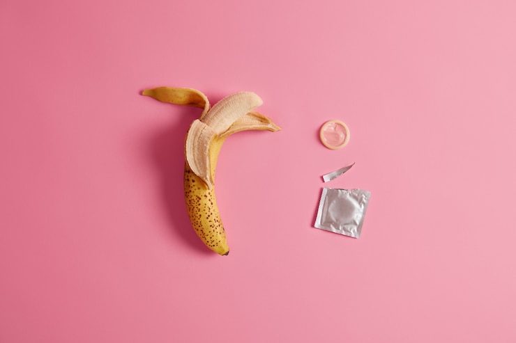 Kostenlose Foto wirksame verhinderung von schwangerschaftsprodukten zu ihrer sicherheit. öffnen sie das kondonpaket mit einer banane.