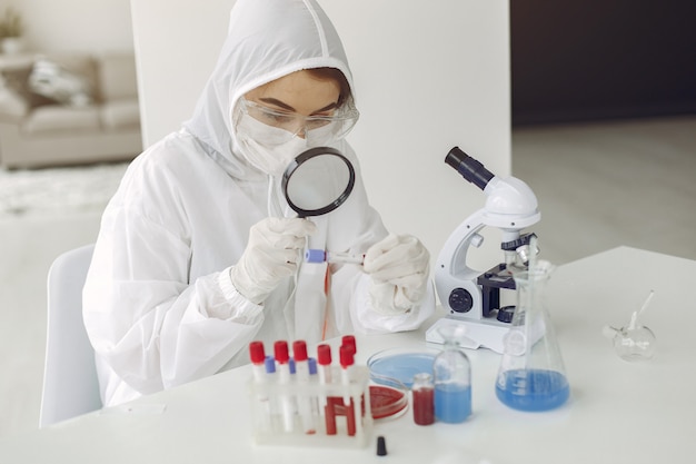 Wissenschaftler in Overallkleidung untersuchen die Coronavirus-Probe in einem Labor