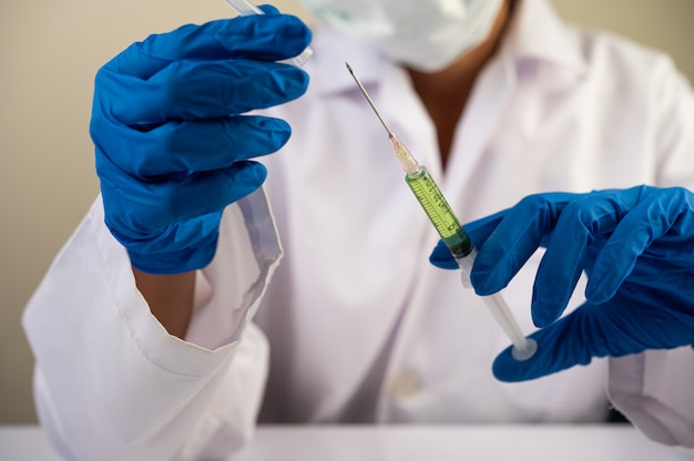 Wissenschaftler tragen Masken und Handschuhe Halten eine Spritze mit einem Impfstoff, um Covid-19 zu verhindern