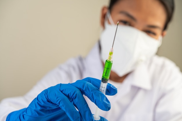Wissenschaftler tragen Masken und Handschuhe Halten eine Spritze mit einem Impfstoff, um Covid-19 zu verhindern