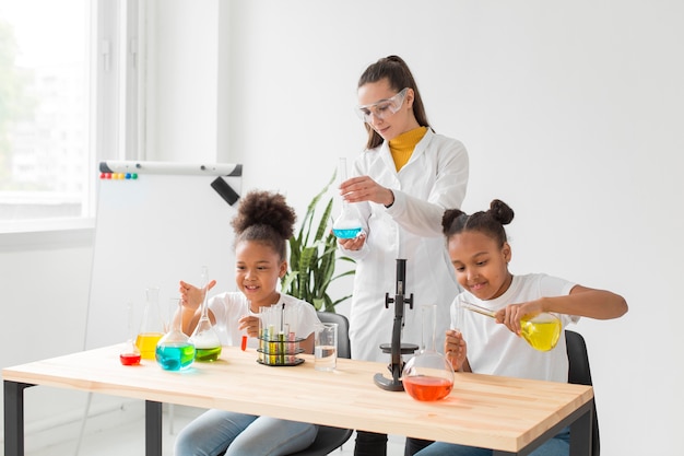 Wissenschaftlerin, die junge Mädchen wissenschaftliche Experimente unterrichtet