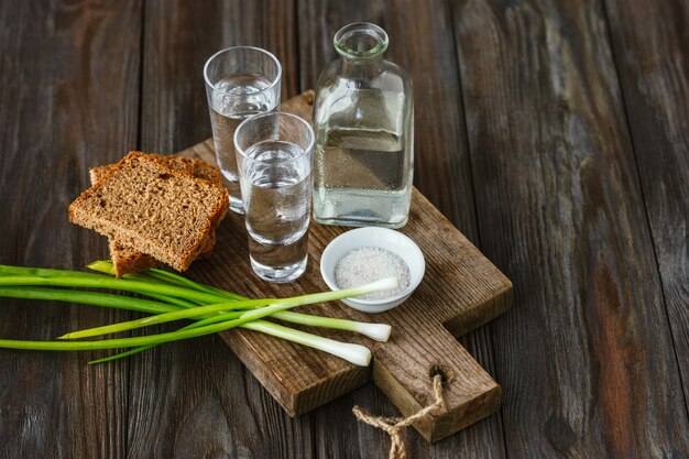 Wodka und traditioneller Snack auf Holzwand