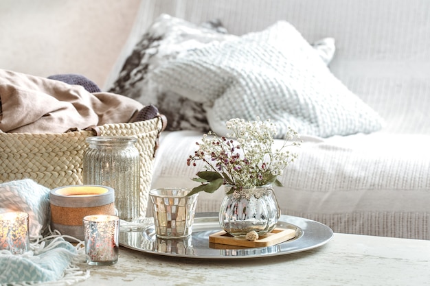 Wohnaccessoires im Innenraum. Eine türkisfarbene Decke und ein Weidenkorb mit einer Vase mit Blumen und Kerzen