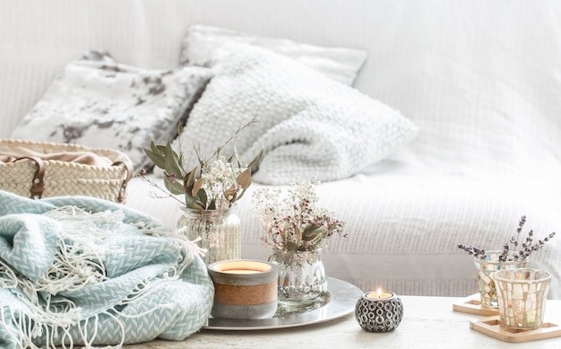 Wohnaccessoires im Innenraum. türkisfarbene Decke und Weidenkorb mit einer Vase mit Blumen und Kerzen