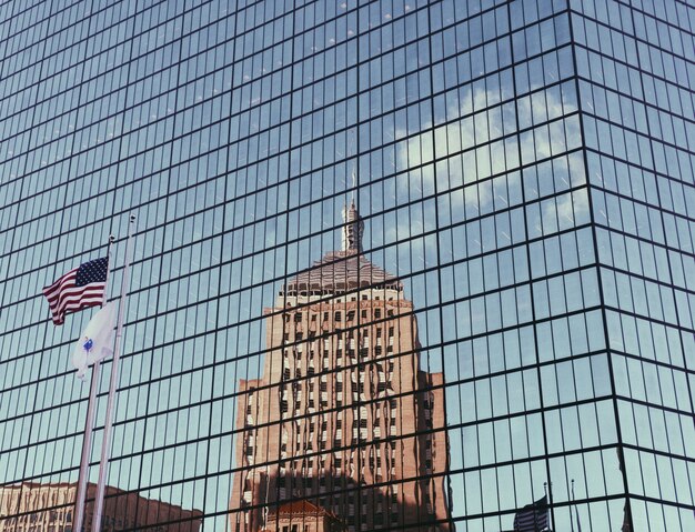 Wolkenkratzergebäude aus Glas mit amerikanischer Flagge und Spiegelung des hohen Gebäudes