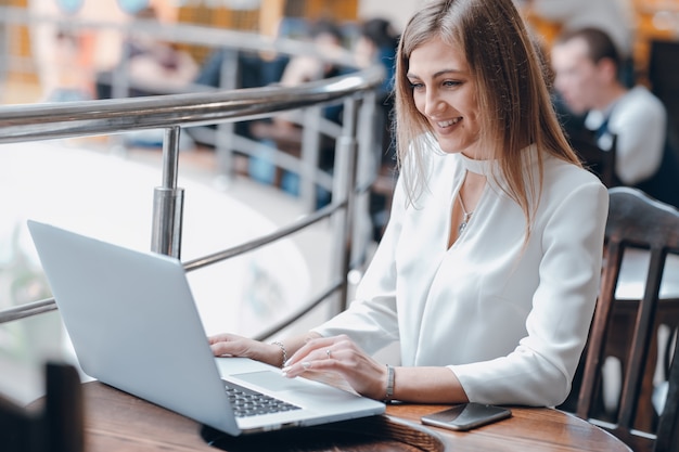 Woman Eingabe auf einem Laptop in einem Café