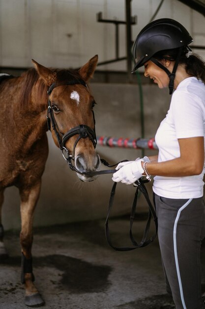 Woman Groomer kümmert sich um und kämmt Haare Pferdemantel nach dem Unterricht Hippodrom. Frau kümmert sich um ein Pferd, wäscht das Pferd nach dem Training.