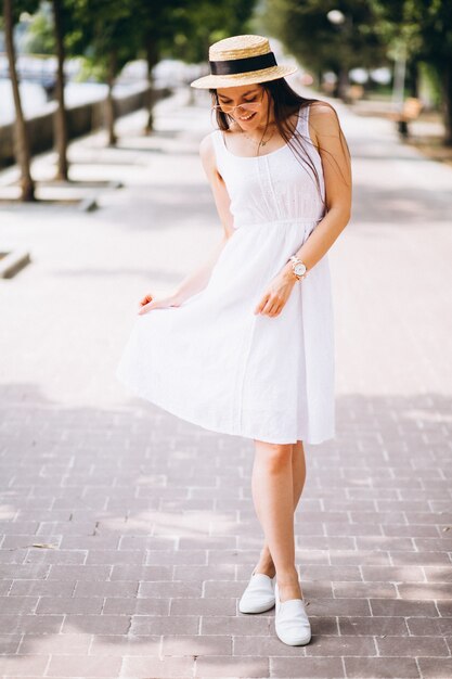 Womanwearing Kleid und Hut draußen im Park