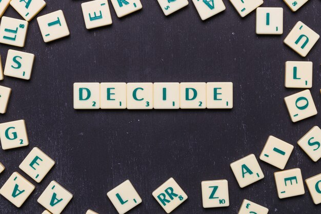 Wort entscheiden in Scrabble-Buchstaben über schwarzem Hintergrund