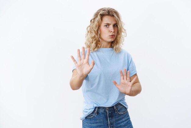 Wow, langsamer Intensive und besorgte Frau, die schwer atmet, die Hände zur Verteidigung hebt, und keine Geste, die die Lippen faltet, tritt alarmiert zurück, als sich weigernde und versuchende ruhige Person, die sich verrückt über der weißen Wand verhält