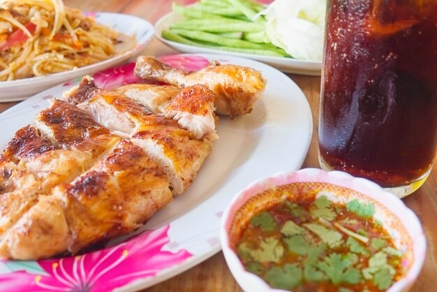 Würzige Mahlzeit nach thailändischer Art, Hähnchen vom Grill mit würzigem Papayasalat und kaltes Getränk