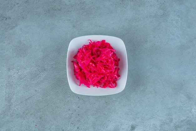 Würziges gehacktes rot fermentiertes Sauerkraut in einer Schüssel auf dem blauen Tisch.