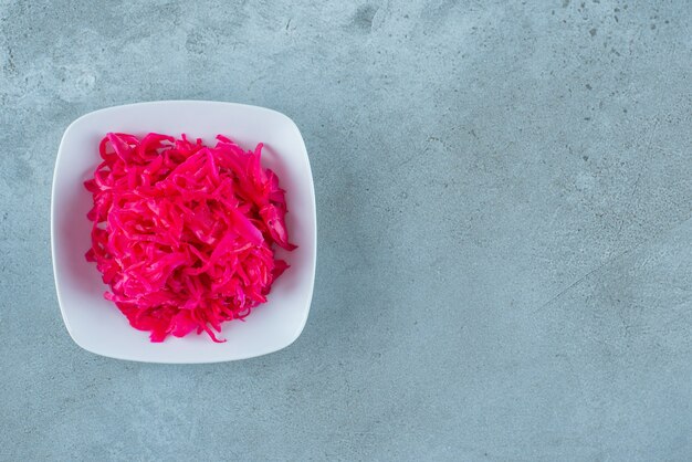 Würziges gehacktes rot fermentiertes Sauerkraut in einer Schüssel auf dem blauen Tisch.