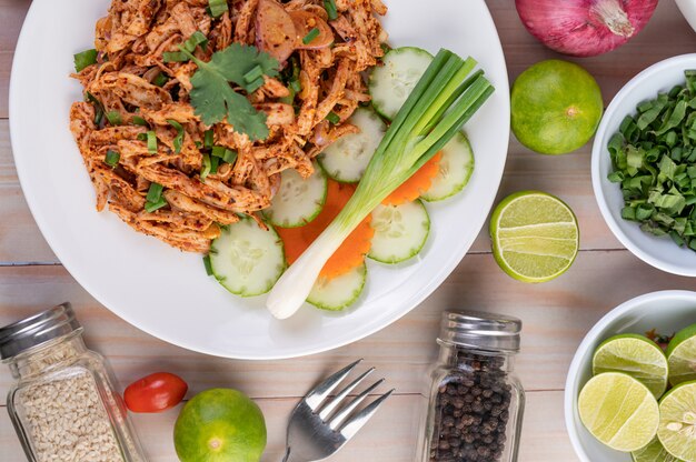 Würziges Hackfleisch auf einem weißen Teller mit Gurke, Salat und Beilagen.