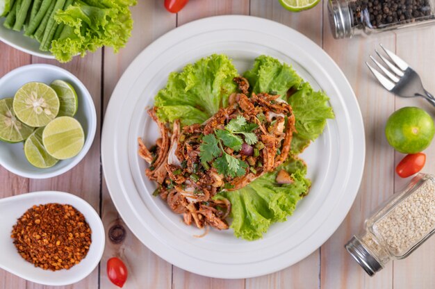 Würziges Hackfleisch auf einem weißen Teller mit Gurke, Salat und Beilagen.