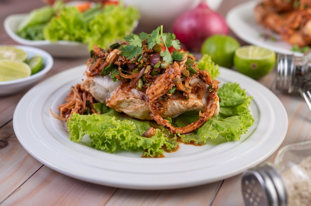 Würziges Hackfleisch auf einem weißen Teller mit Gurke, Salat und Beilagen.