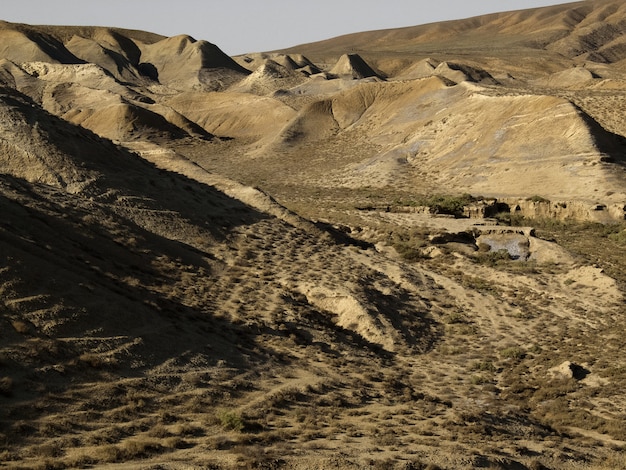 Wüstenstandort einsam und ruhig mit braunem Sand gegen blauen Himmel