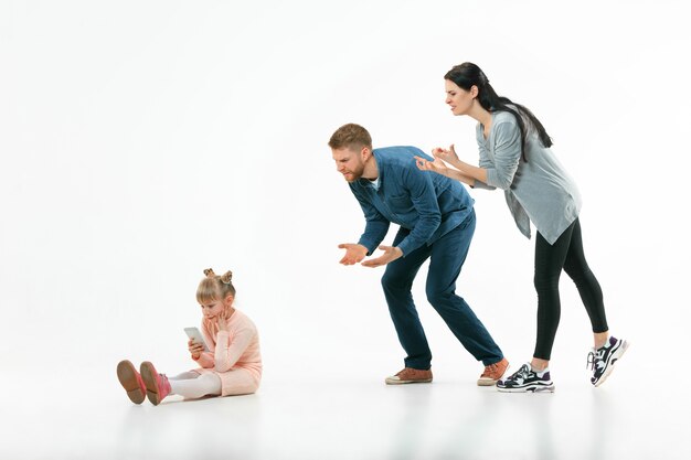 Wütende Eltern schimpfen zu Hause mit ihrer Tochter. Studioaufnahme der emotionalen Familie. Menschliche Emotionen, Kindheit, Probleme, Konflikte, häusliches Leben, Beziehungskonzept