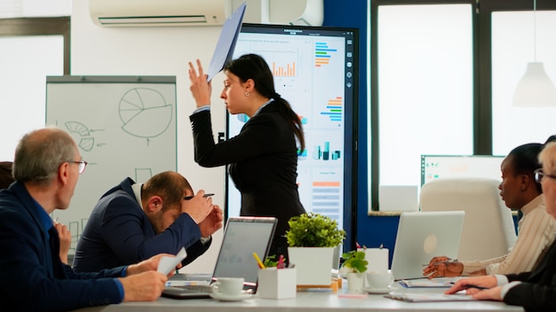 Wütende Managerin, die sich über einen schlechten Geschäftsvertrag streitet, verschiedene Kollegen, die Konflikte über das Sitzen von Dokumenten auf dem Schreibtisch während des Brainstormings von Partnern haben, die im Sitzungssaal arbeiten