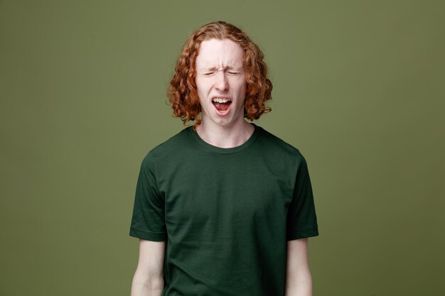 Wütender junger gutaussehender Kerl mit grünem T-Shirt isoliert auf grünem Hintergrund
