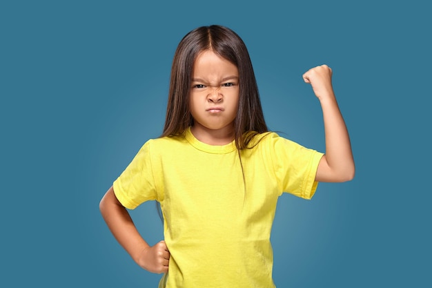 Wütendes kleines Kind, das Frustration und Meinungsverschiedenheiten auf blauem Hintergrund zeigt