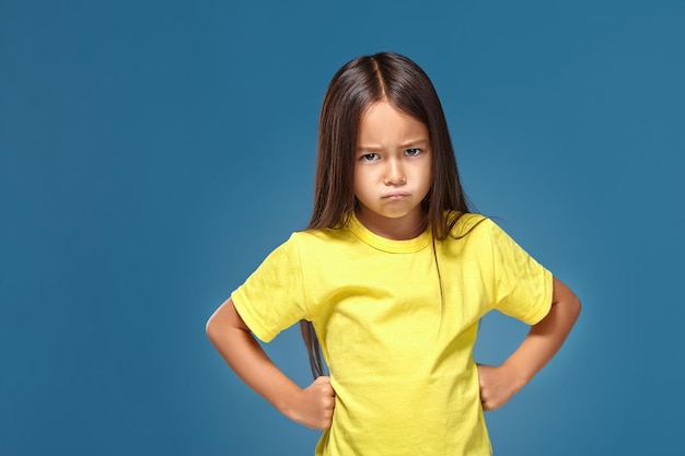 Wütendes kleines Kind, das Frustration und Meinungsverschiedenheiten auf blauem Hintergrund zeigt
