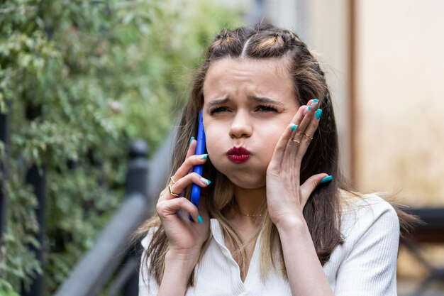 Wütendes Mädchen, das am Telefon spricht und ihre Lippen faltet