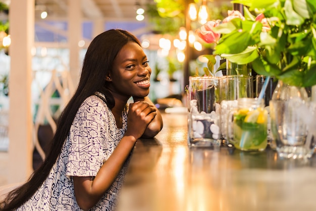 Wunderschöne afrikanische Frau, die Limonade trinkt, die im Café sitzt.