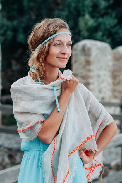 Wunderschöne Dame im langen blauen Kleid, das tagsüber steht und lächelt.