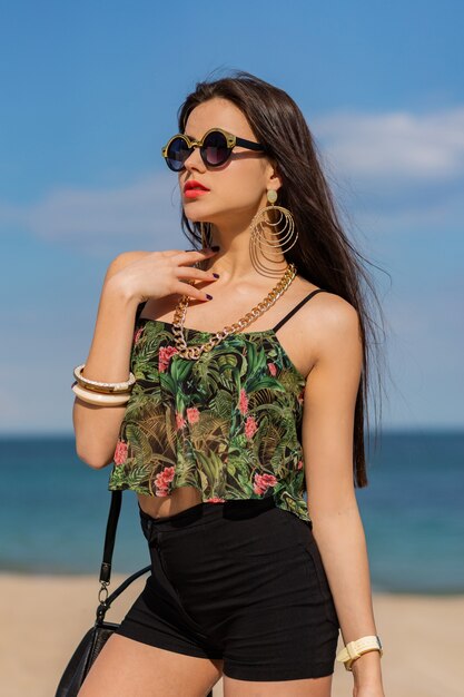 Wunderschöne Frau mit langen glatten Haaren, die an einem erstaunlichen tropischen Strand posng.