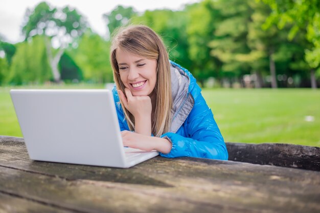 Wunderschöne junge Brünette Mädchen mit ihrem Laptop in sunlit Park.