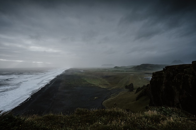 Wunderschöne Landschaft des Meeres, umgeben von Felsformationen im Nebel in Island