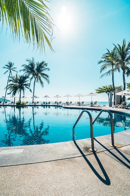 Wunderschönen tropischen Strand und Meer mit Sonnenschirm und Stuhl rund um den Pool