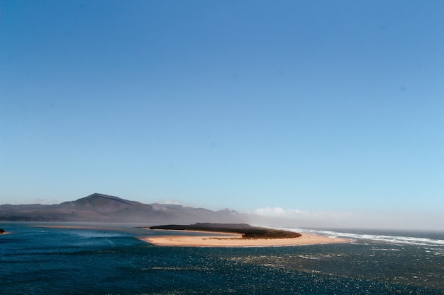 Wunderschöner Blick auf das Meer mit einer kleinen Sandinsel in der Mitte und Hügeln