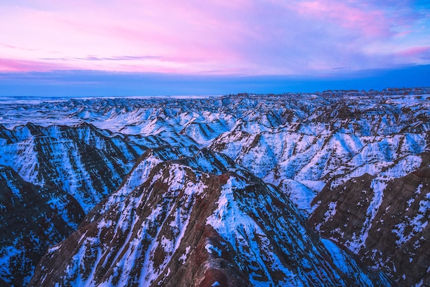 Kostenloses Foto wunderschöner rosa sonnenaufgang über schneebedeckten gipfeln im badlands national park south dakota