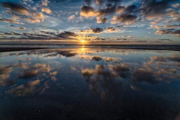 Wunderschöner Sonnenaufgang, der sich im Meer spiegelt und die perfekte Kulisse für morgendliche Spaziergänge schafft
