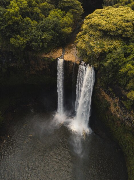 Wunderschöner Wasserfall, der in den Fluss fließt, umgeben von Grün