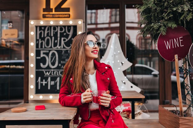 Wunderschönes langhaariges weibliches Modell, das im Frühlingstag im Café sitzt